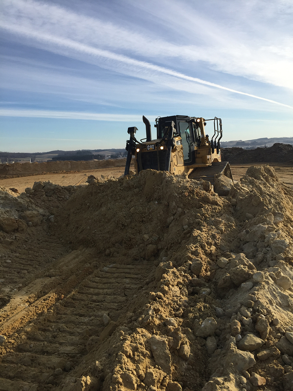 Track dozer pushing soil across an active earthmoving site