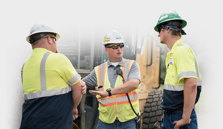 Jay Collup discussing equipment operation with crew members at a jobsite